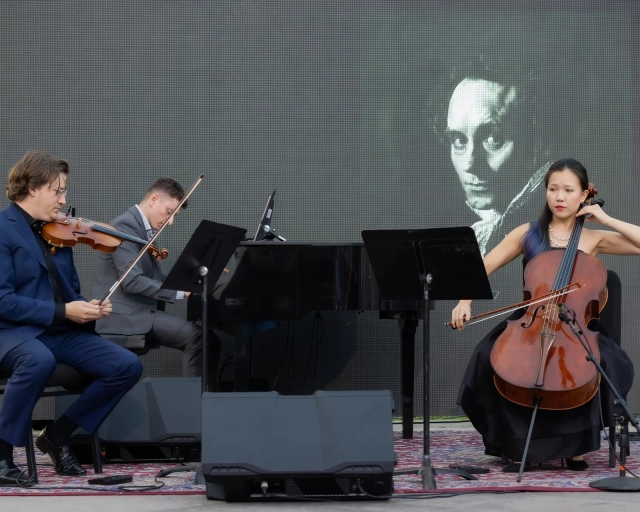 A violinist, pianist and cellist playing on an outdoor stage at California Plaza.