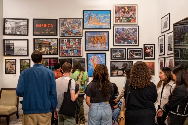 Visitors gathered in front of a salon-style hang of framed paintings, photographs and collage in the Emerging Gallery.