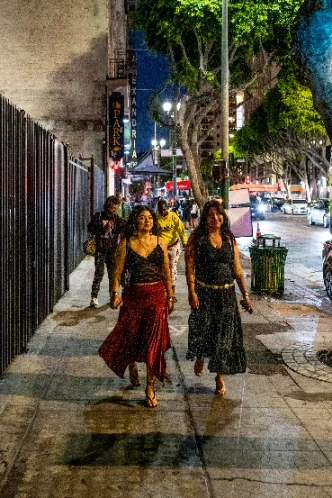 Two people walking a Downtown sidewalk at night under a marquee.