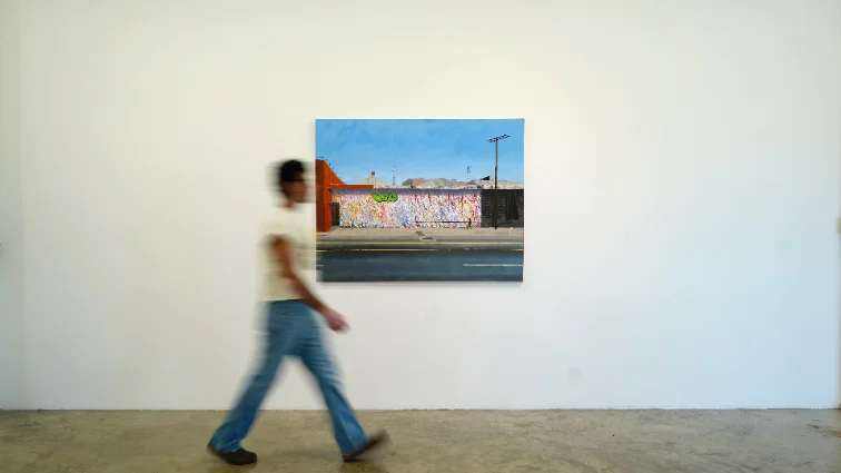 A visitor walking past a painting in a Fashion District gallery.