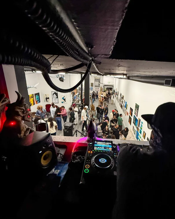 A DJ playing above a packed, art-lined room in the Historic Core.