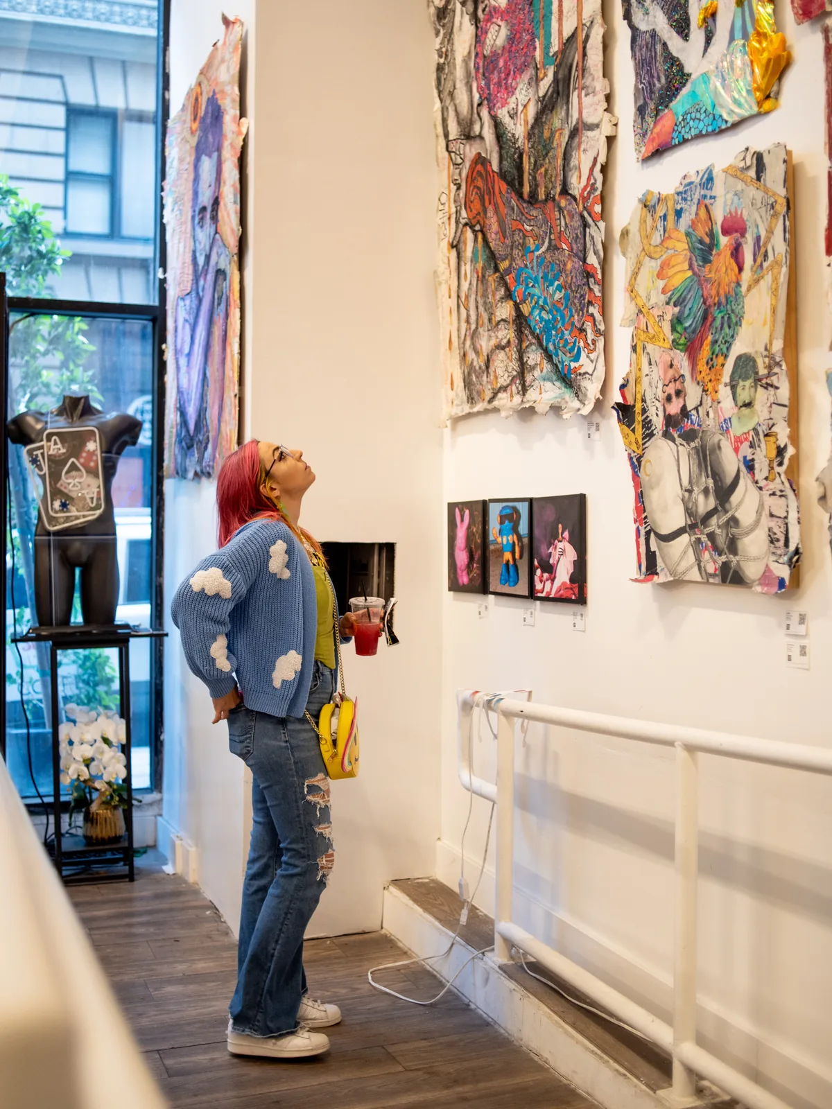 A visitor looking up at a wall of paintings inside a Downtown gallery on ArtNight.